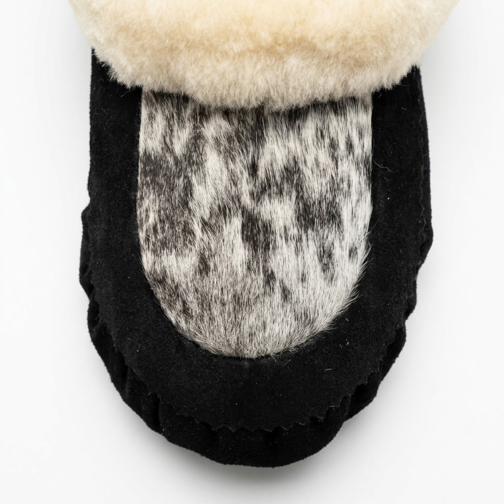 Close-up of the natural speckled hair-on cowhide vamp and hand-stitched toe on a black suede Snowfall moccasin.